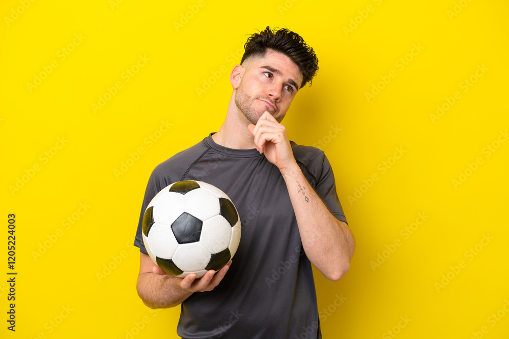 Handsome young football player man isolated on yellow background and looking up Handsome young football player man isolated on yellow background and looking up