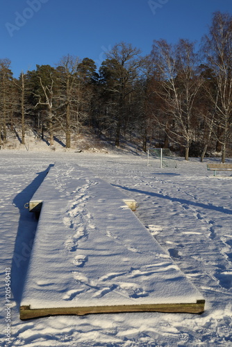 Snow on a portable bridge at land. Sunny winter day in January 2025. Maltesholmsbadet, Hässelby, Sweden.  photo