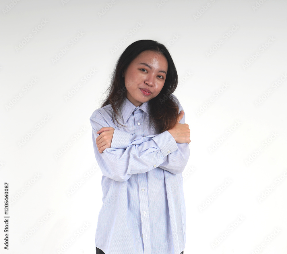 Asian women with light blue shirt and long hair hugging herself. Self love themed photo isolated on horizontal white background from front view angle. Asian women with light blue shirt and long hair hugging herself. Self love themed photo isolated on horizontal white background from front view angle.