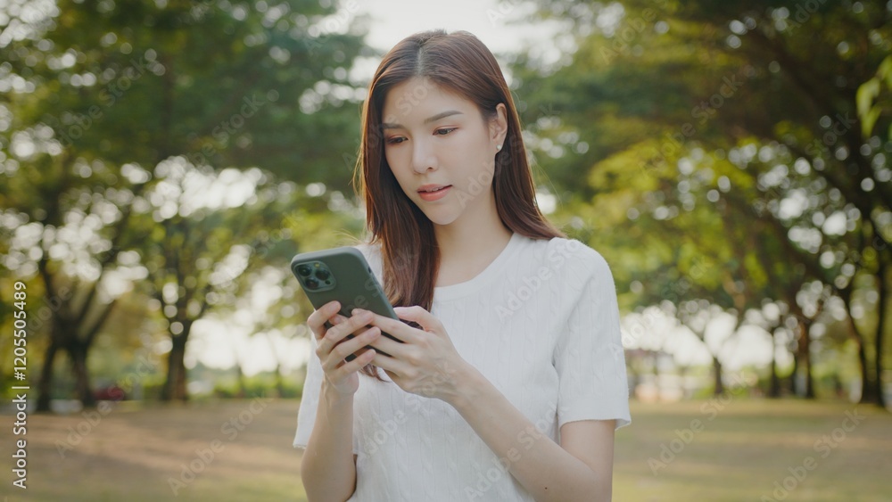 Happy woman texting on a phone. Business asian woman using mobile phone during checking an email or social media on internet in the sunny park. Talk with Ai, Mobile Device Happy woman texting on a phone. Business asian woman using mobile phone during checking an email or social media on internet in the sunny park. Talk with Ai, Mobile Device