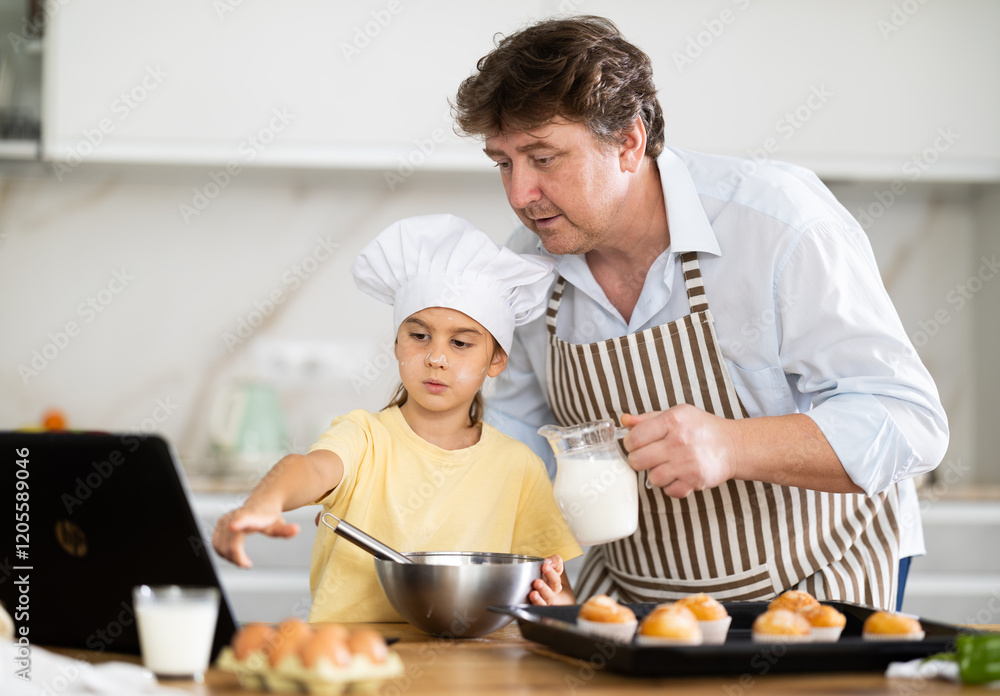 Father and daughter preparing muffins in kitchen