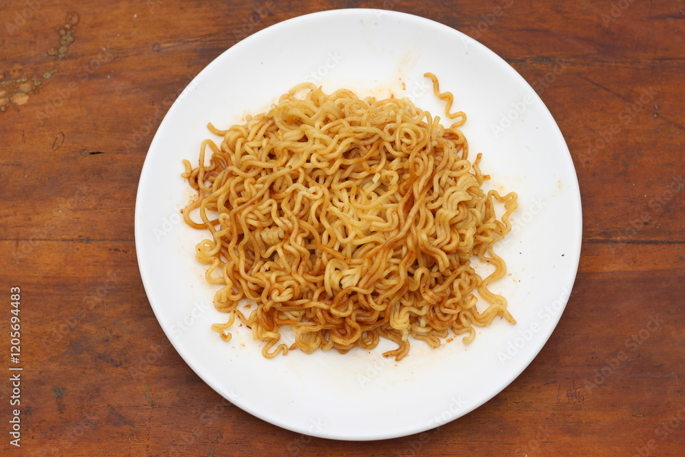 Top view of instant noodles spicy in white plate on wooden table background. Top view of instant noodles spicy in white plate on wooden table background.