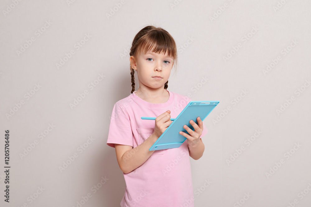 A little girl with a toy graphics tablet and a stylus A little girl with a toy graphics tablet and a stylus