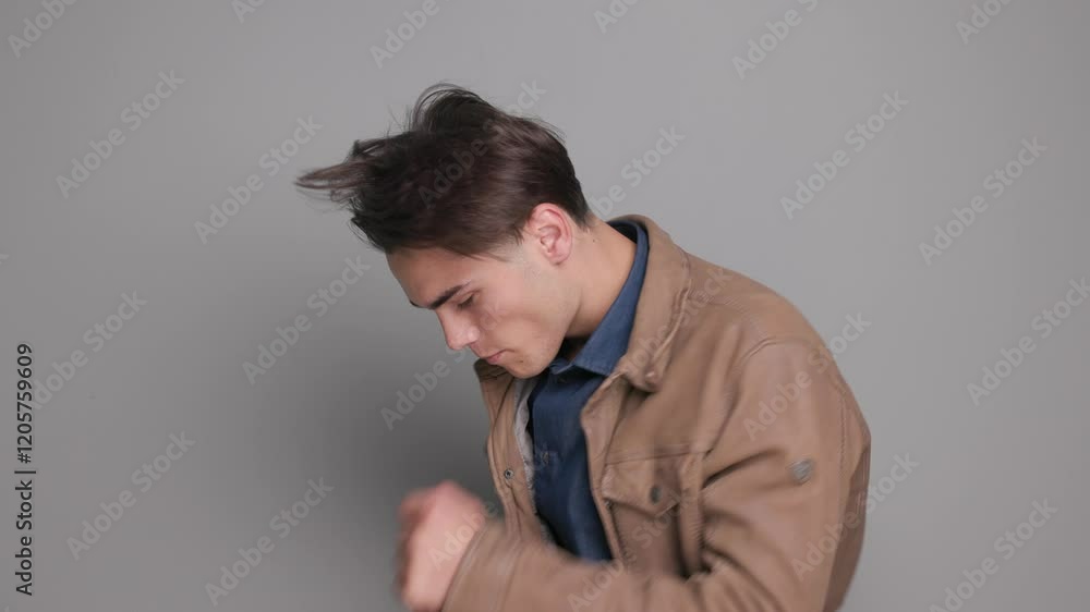 happy casual man reading a text on mobile phone and dancing, celebrating a win while moving to side on gray background happy casual man reading a text on mobile phone and dancing, celebrating a win while moving to side on gray background