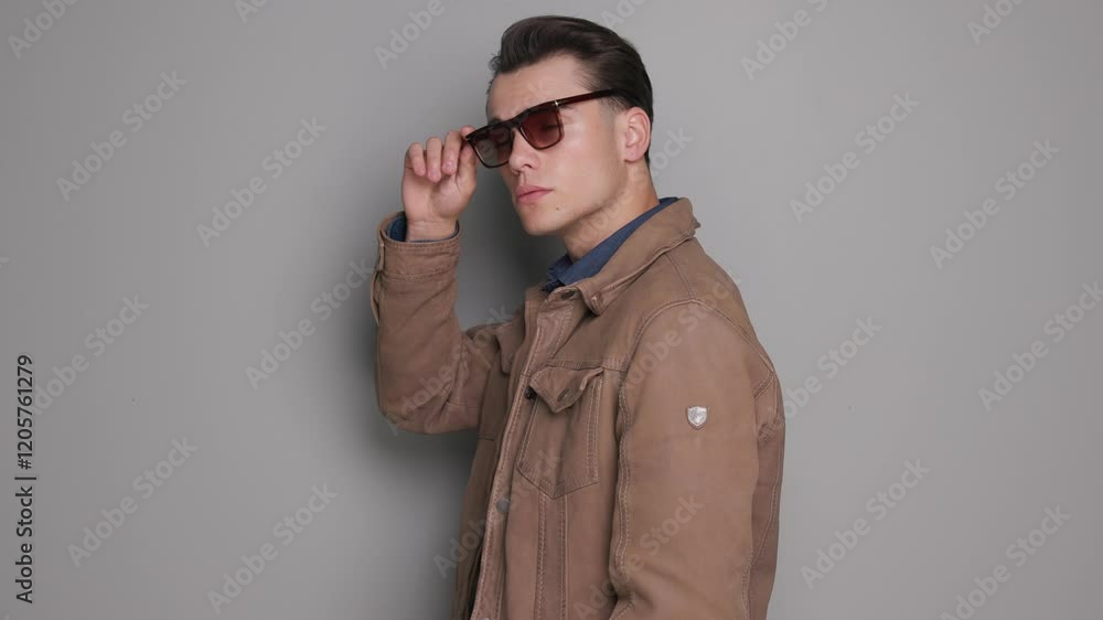 attractive casual man turning to side while taking off sunglasses and posing sexy whie looking up and to side attractive casual man turning to side while taking off sunglasses and posing sexy whie looking up and to side