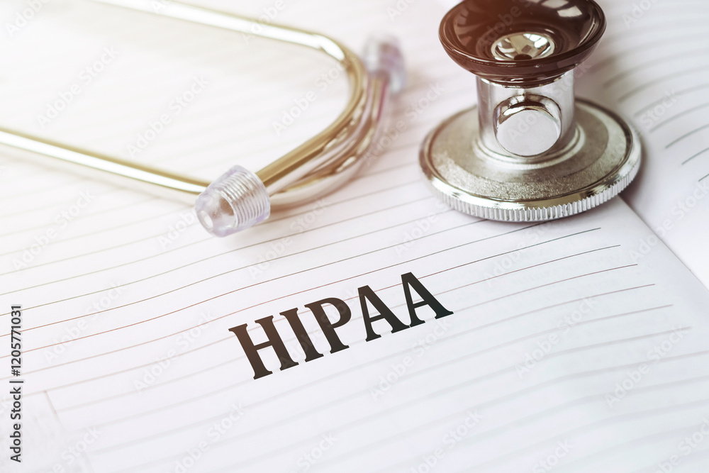 A silver stethoscope rests on a lined notebook with the word HIPAA written in black ink. A silver stethoscope rests on a lined notebook with the word HIPAA written in black ink.