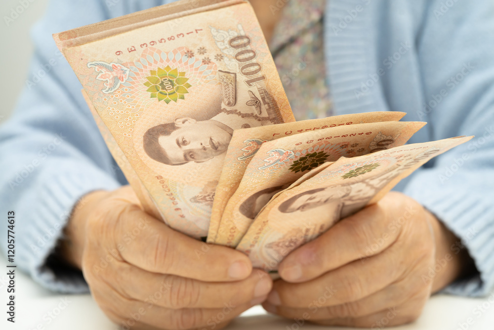 Asian elder senior woman patient holding Thai banknotes money in her hand, Cost of living and medical care. Asian elder senior woman patient holding Thai banknotes money in her hand, Cost of living and medical care.