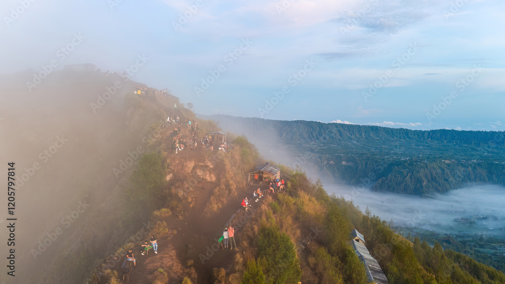 A group of hikers on a foggy mountain peak in Bali, overlooking the stunning Mount Batur volcano. The image highlights the natural beauty and allure of this popular hiking destination