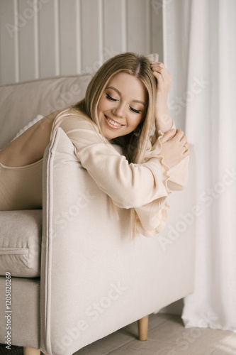 Portrait of smiling blonde woman with beautiful white smile in modern stylish beige interior