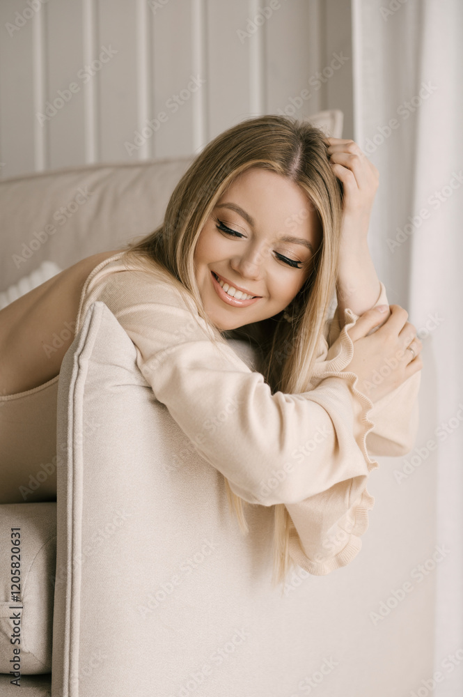 Portrait of smiling blonde woman with beautiful white smile in modern stylish beige interior