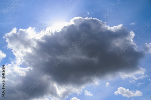 Rays of sunshine shine through a cloud in the blue sky. photo