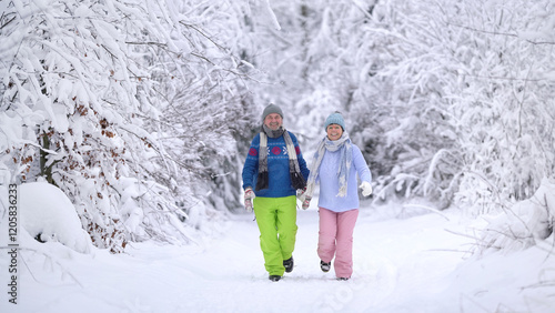 together walking hand in hand through the snowy winter landscape, smiling active couple