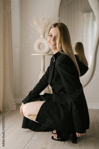 Beautiful blonde woman posing in beautiful modern stylish beige interior on photo of large mirror