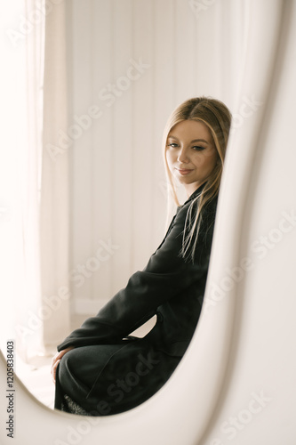 Beautiful blonde woman posing in beautiful modern stylish beige interior on photo of large mirror