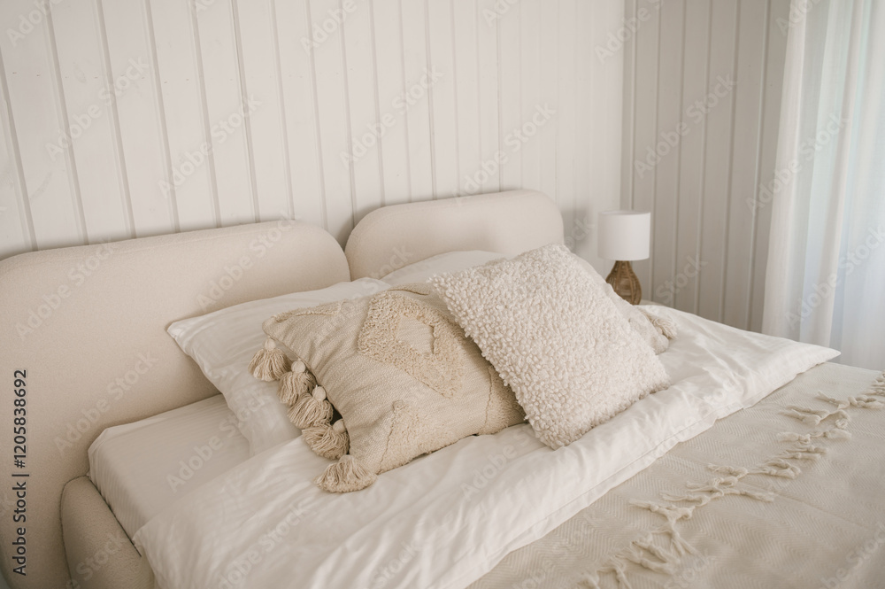 Beautiful light beige interior with soft white bed decorated with pillows in japandi and wawabi sabi style, cozy home concept