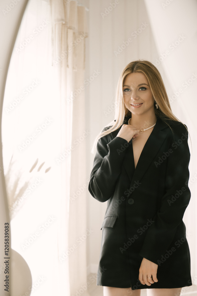 Beautiful blonde woman posing in beautiful modern stylish beige interior on photo of large mirror