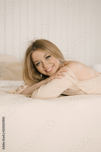 Portrait of smiling blonde woman with beautiful white smile in modern stylish beige interior
