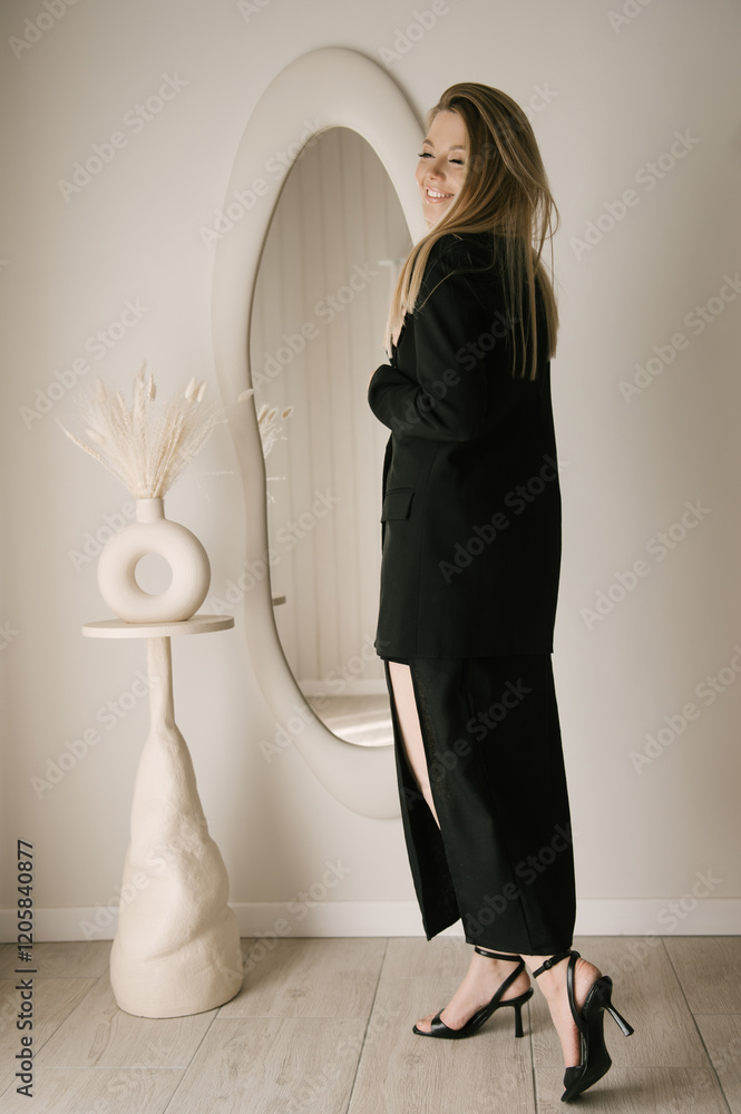 Beautiful blonde woman posing in beautiful modern stylish beige interior on photo of large mirror