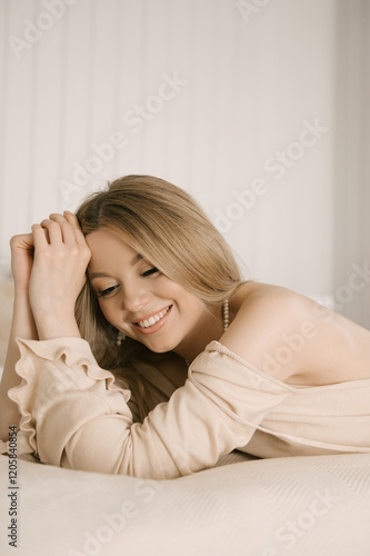 Obraz na płótnie Beautiful blonde woman posing on light bed in modern stylish beige interior w salonie