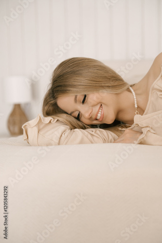 Obraz na płótnie Beautiful blonde woman posing on light bed in modern stylish beige interior w salonie
