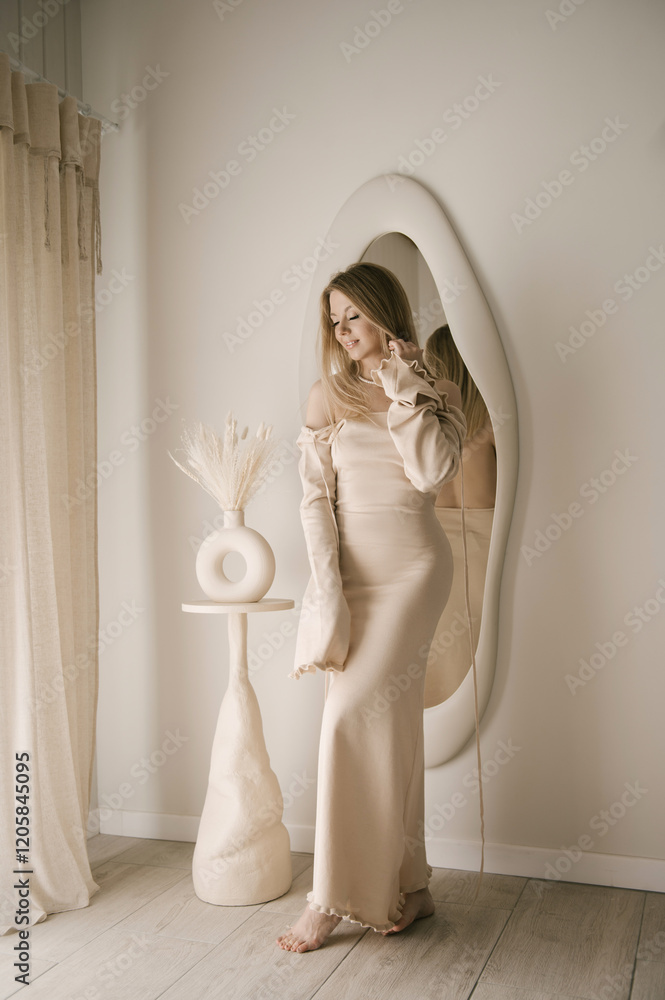 Beautiful blonde woman posing in beautiful modern stylish beige interior on photo of large mirror