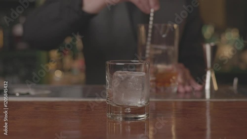 Close-up of a bartender serving a freshly made cocktail in a glass at a modern bar
