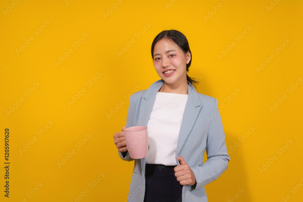 Portrait of a cheerful asian businesswoman holding a pink mug on a yellow background Portrait of a cheerful asian businesswoman holding a pink mug on a yellow background
