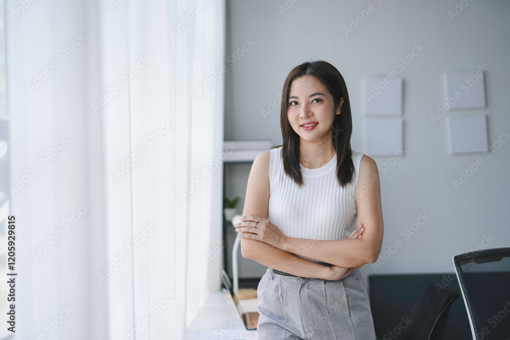 Portrait of smiling asian businesswoman standing with arms crossed in modern office Portrait of smiling asian businesswoman standing with arms crossed in modern office