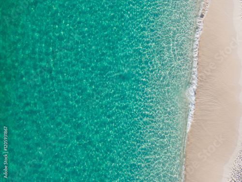 Fototapeta Naklejka Na Ścianę i Meble -  Crystal-clear turquoise waters meet soft sandy shore in this stunning aerial view of a tropical beach in the Bahamas.  