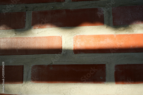 Shadows play on a textured brick wall during late afternoon light photo