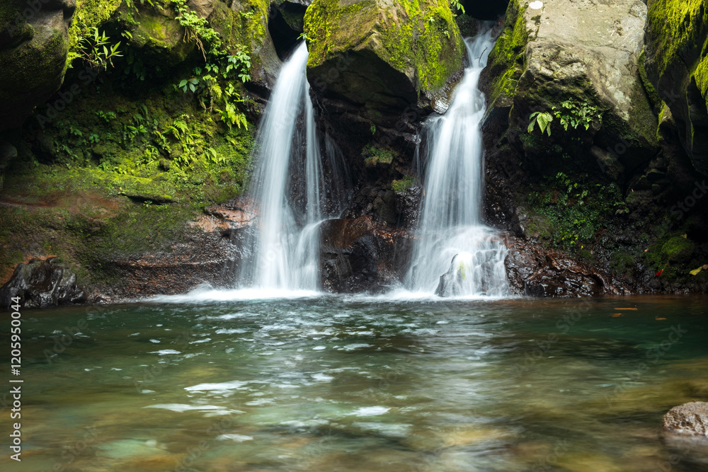 Fototapeta premium Moss-Covered Rocks Framing a Serene Waterfall