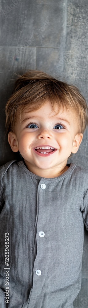 A joyful toddler smiling brightly on a gray background, radiating pure happiness. A joyful toddler smiling brightly on a gray background, radiating pure happiness.