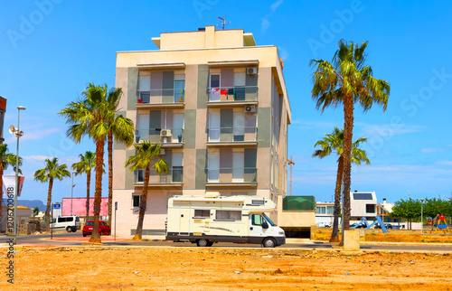Campervan on parking on street near House. Family camper van at home during traveling. Motorhome lifestyle travel to sea. Travel on Campervan to Spain coast. Caravaning Parking at apartments hotel.