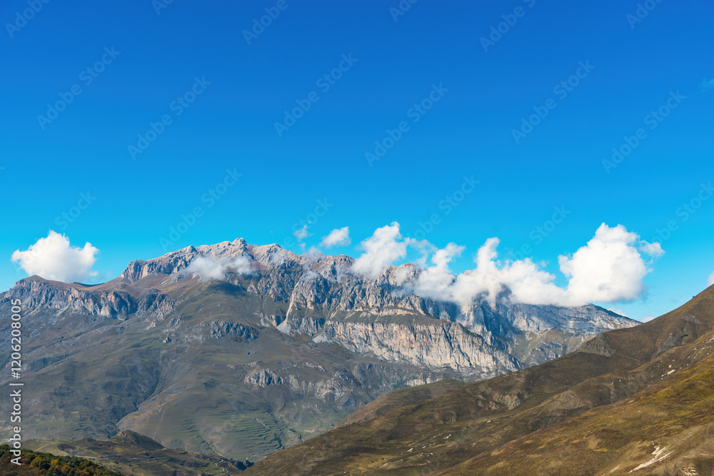 a view of the mountain tops shrouded in clouds against the blue sky. natural light a view of the mountain tops shrouded in clouds against the blue sky. natural light