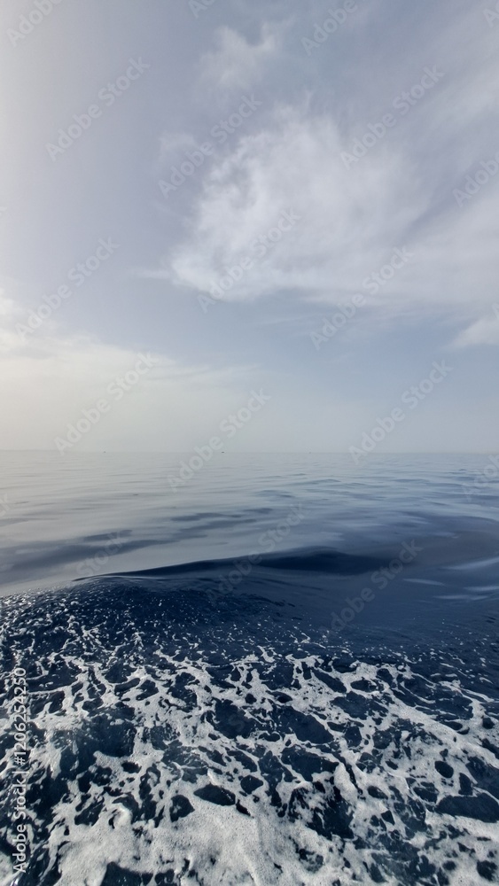 A close-up shot of choppy ocean water creates a dynamic foreground of white foam against a smooth expanse of blue, with a hazy sky above, evoking a sense of movement, energy, the vastness of the sea A close-up shot of choppy ocean water creates a dynamic foreground of white foam against a smooth expanse of blue, with a hazy sky above, evoking a sense of movement, energy, the vastness of the sea