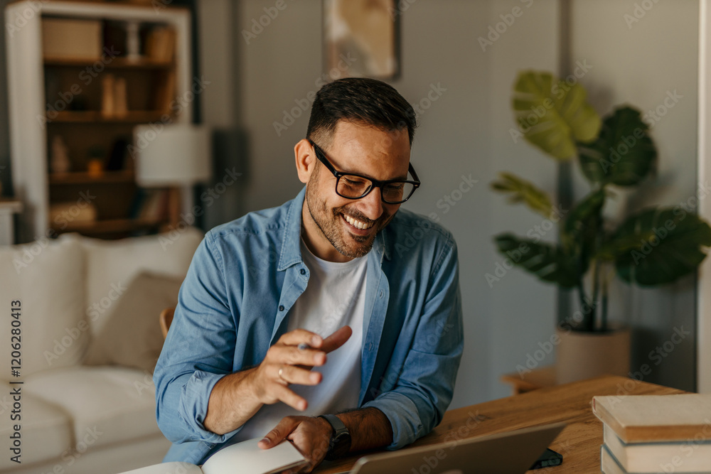 Fototapeta premium Comfortable workspace. Man balancing work and home finances in a bright living room