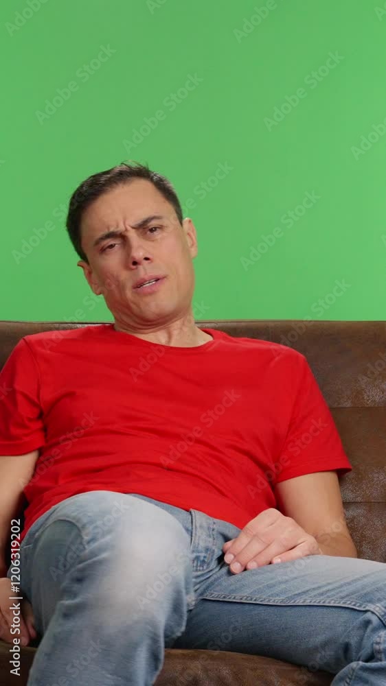Man gets bored watching tv and starts using his phone Man gets bored watching tv and starts using his phone