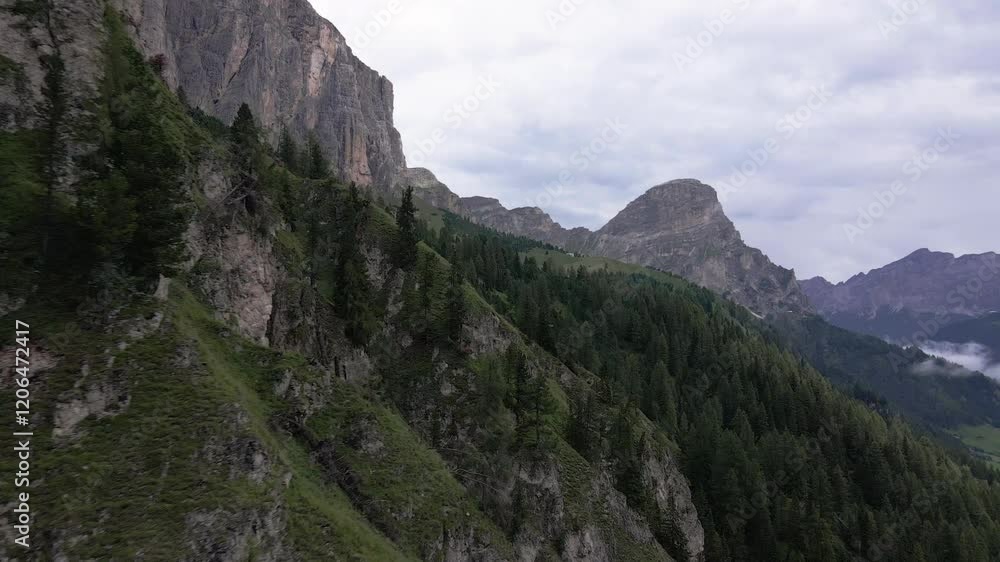 A serene view of the Dolomites, Italy, showcasing steep cliffs, lush green slopes, dense pine forests, and a cloudy sky. A serene view of the Dolomites, Italy, showcasing steep cliffs, lush green slopes, dense pine forests, and a cloudy sky.