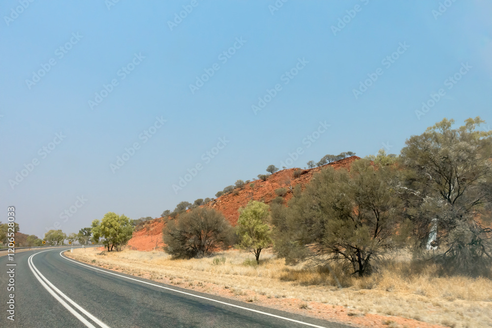 Fototapeta premium Bend in the road near Stuarts Well in the Northern Territory of Australia, showing dry outback landcape and flora.