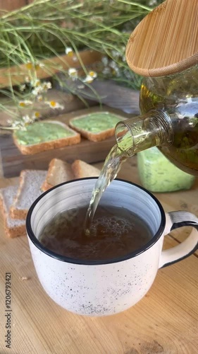 herbal tea. pouring tea from a teapot into a mug