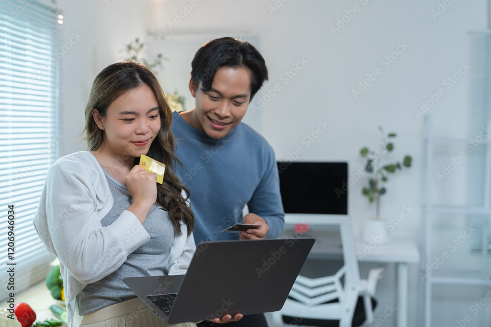 © crizzystudio - Happy asian couple holding credit card and using laptop computer making online shopping or payment banking at home together, technology money wallet and online payment concept