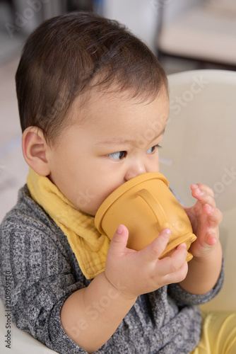 there is a baby sitting in a high chair drinking from a cup