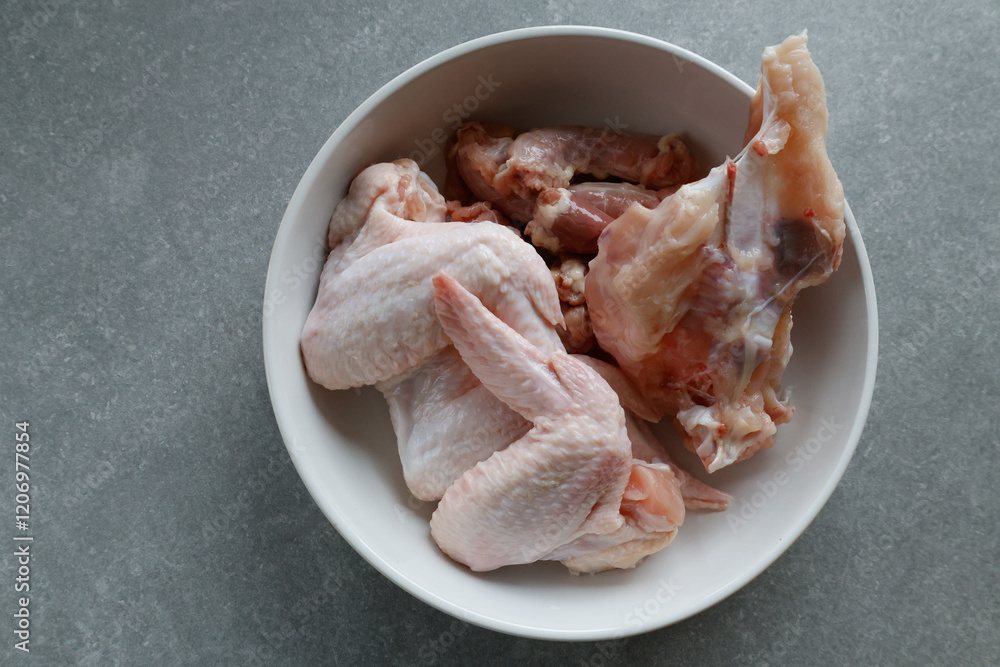 Raw chicken pieces in a white bowl on the counter. Raw chicken pieces in a white bowl on the counter.