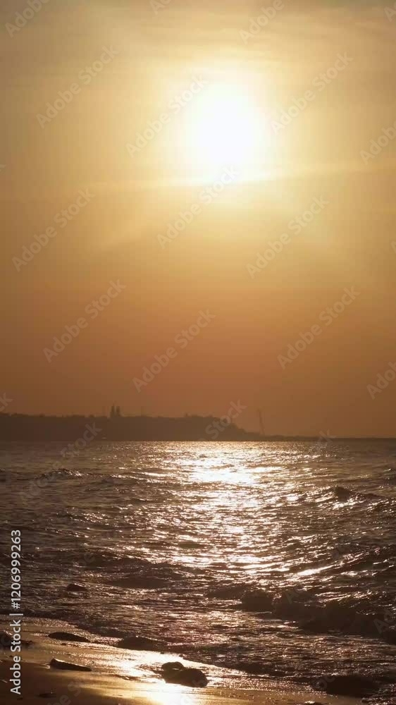 Orange sun over the beach. Sunset on a calm sea. Sandy shore near the water in the evening. Path of light on the waves. Orange sun over the beach. Sunset on a calm sea. Sandy shore near the water in the evening. Path of light on the waves.