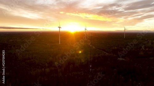 Wind turbines generating clean energy at sunset over forest photo