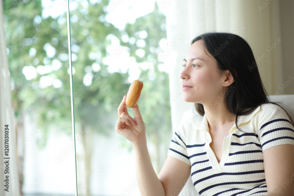 Asian woman holding doughnut looking through window Asian woman holding doughnut looking through window