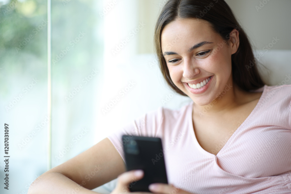 Happy woman using cell phone smiling at home Happy woman using cell phone smiling at home