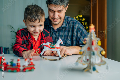 Father near son playing with rocking horse at home photo