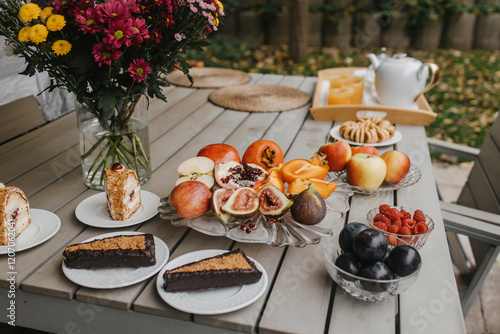 Pastries with fruits and drinks served on table in backyard photo