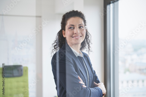 Smiling mature businesswoman with arms crossed seen through glass photo